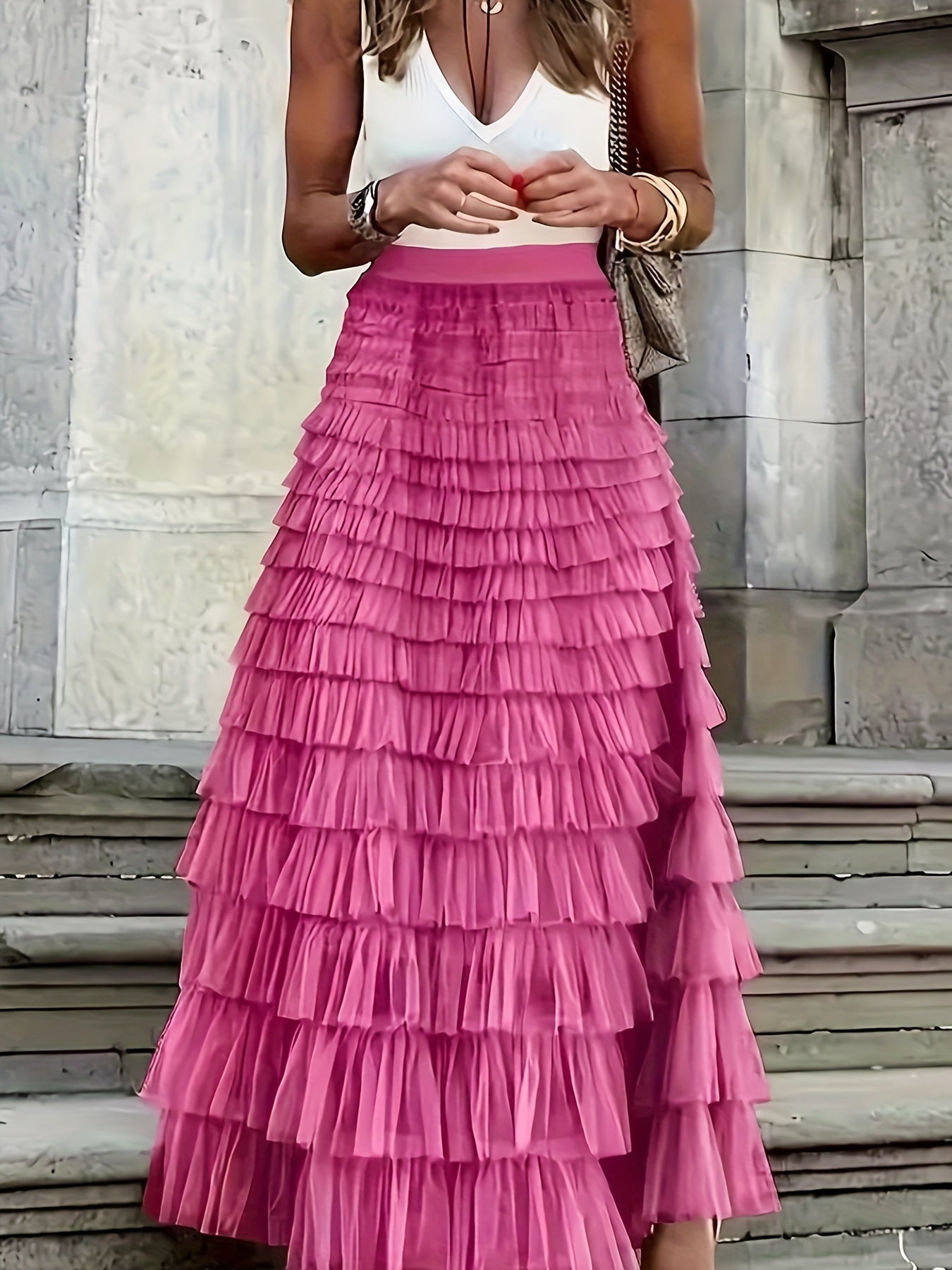 Woman wearing the Sophie Women's Layered Tulle Skirt, a ruffled skirt with multiple soft layers, creating a flowing and voluminous look, styled with a sleeveless top and accessories, standing on steps outdoors.