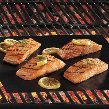 Non-stick grill mat placed on a barbecue grill with grilled salmon fillets and lemon slices, showcasing even cooking and ease of use.