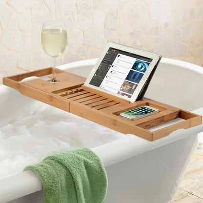 Bath tray with a multi-functional design holding a glass of wine, tablet, and smartphone on a bathtub, showcasing its compartments and adjustable layout for added convenience and relaxation.