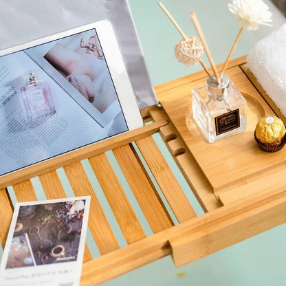 Bath tray with a multi-functional design holding a glass of wine, tablet, and smartphone on a bathtub, showcasing its compartments and adjustable layout for added convenience and relaxation.