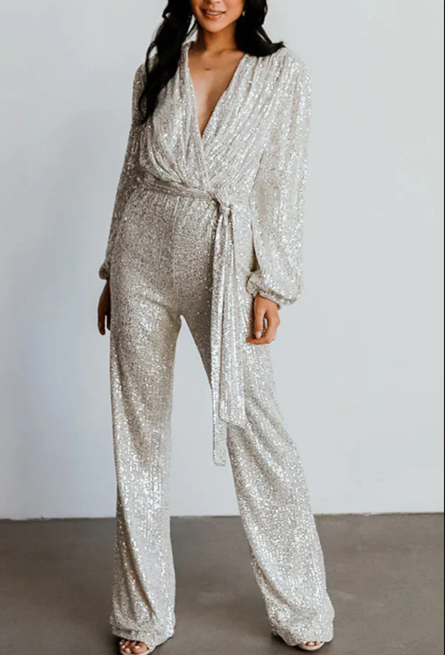 Model wearing the Isabella | Glamorous Sequin Jumpsuit, featuring a wrap-style top, long sleeves, and a wide-leg cut adorned with sparkling sequins. Perfect for special occasions, this jumpsuit combines elegance and comfort for a bold, statement-making look.