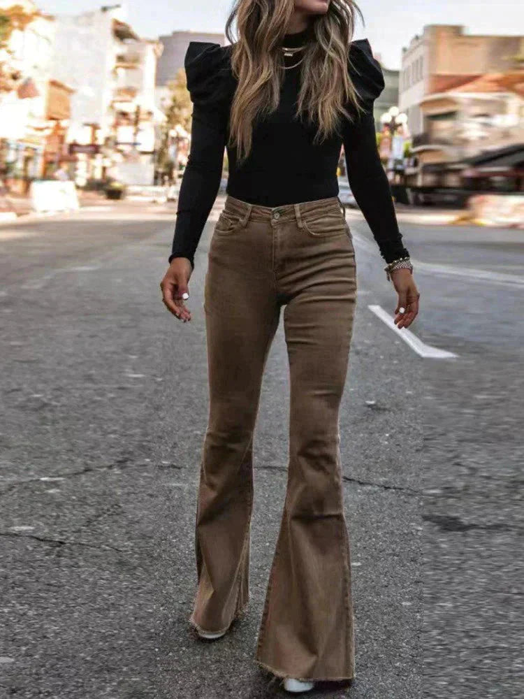 Full-body view of a woman wearing Harper high-waisted flare pants in a retro style, paired with a cropped top, holding a handbag, standing outdoors.