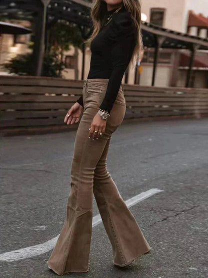 Full-body view of a woman wearing Harper high-waisted flare pants in a retro style, paired with a cropped top, holding a handbag, standing outdoors.