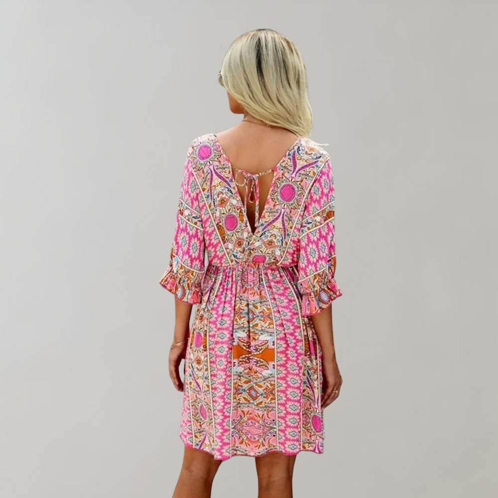 Woman wearing a bohemian-style dress with a flowy fit, featuring intricate patterns and a casual, elegant design.
