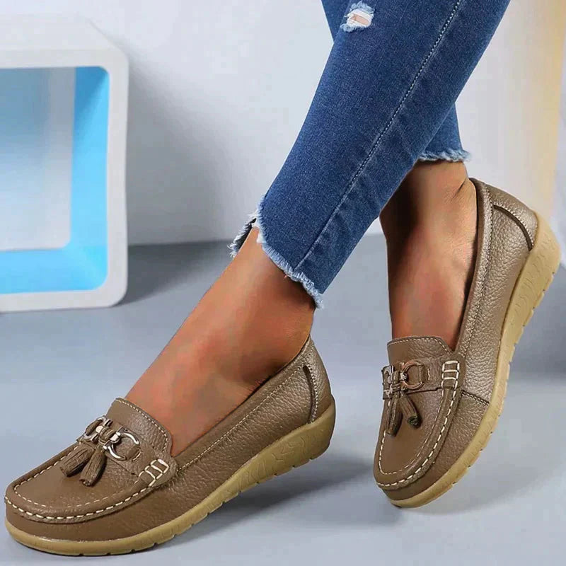 A pair of Grace Women's Classic Loafer Shoes featuring a stylish buckle detail and stitched accents, worn by a person. These loafers combine elegance with comfort, making them suitable for both casual and professional wear.