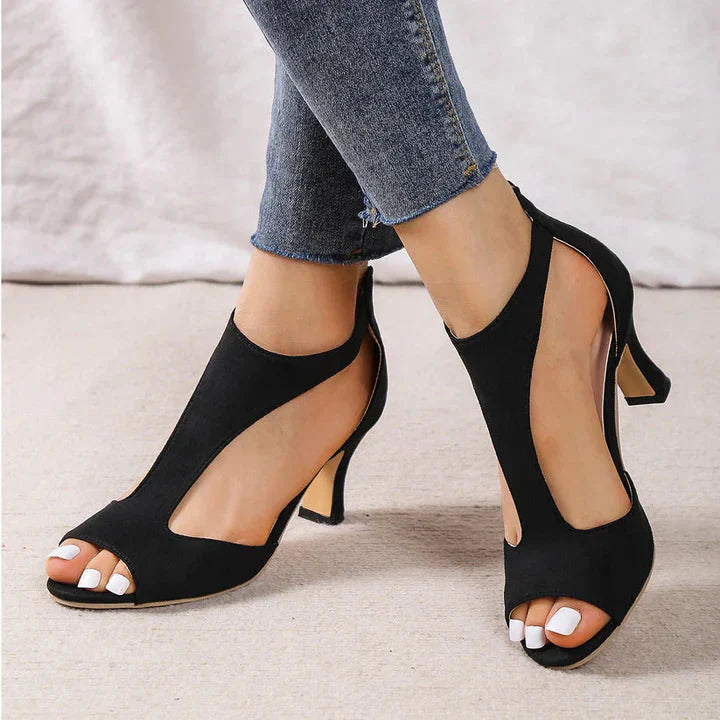 A pair of Sophia Women's Elegant Peep-Toe Heels with a stylish cut-out design, worn by a person. These heels feature a chic peep-toe style and mid-height heel, showcasing an elegant and fashionable look suitable for formal or special occasions.