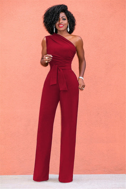 A woman wearing a stylish one-shoulder jumpsuit with a tie waist and wide-leg design, creating an elegant and modern look. The outfit is perfect for formal occasions or evening events, combining sophistication with a bold fashion statement.