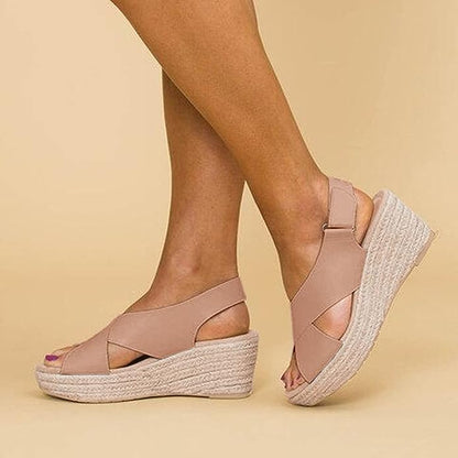 A close-up of a pair of Elena Women's Elegant Wedge Sandals being worn, featuring a stylish cross-strap design and a comfortable wedge sole. These sandals offer a blend of elegance and comfort, ideal for casual or dressy occasions.