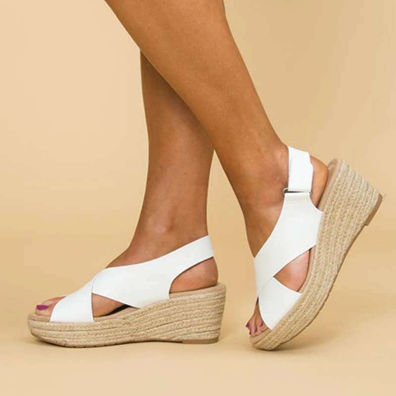 A close-up of a pair of Elena Women's Elegant Wedge Sandals being worn, featuring a stylish cross-strap design and a comfortable wedge sole. These sandals offer a blend of elegance and comfort, ideal for casual or dressy occasions.