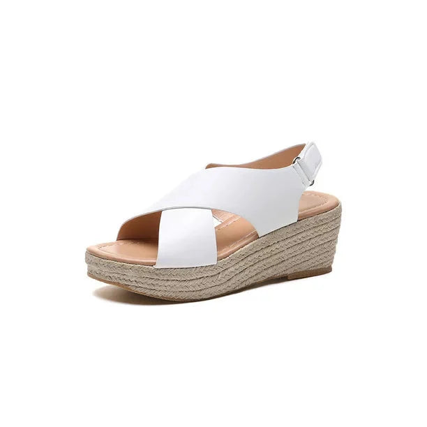 A close-up of a pair of Elena Women's Elegant Wedge Sandals being worn, featuring a stylish cross-strap design and a comfortable wedge sole. These sandals offer a blend of elegance and comfort, ideal for casual or dressy occasions.