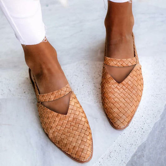 Close-up of a pair of woven slip-on sandals worn with rolled-up pants, showcasing a stylish V-shaped cutout design and casual elegance for effortless, everyday wear.