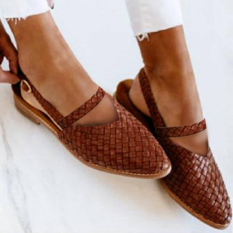 Close-up of a pair of woven slip-on sandals worn with rolled-up pants, showcasing a stylish V-shaped cutout design and casual elegance for effortless, everyday wear.