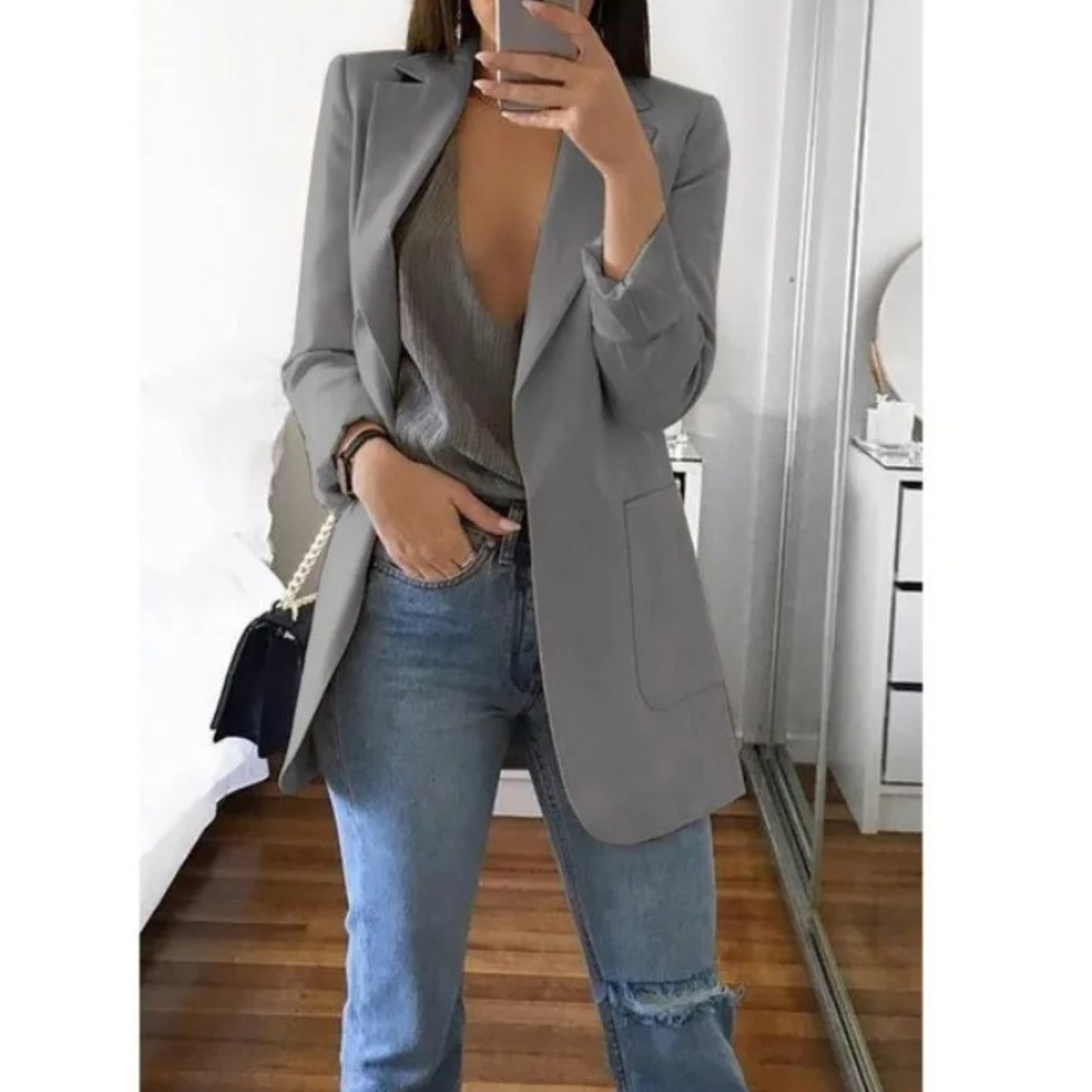 Femme portant le blazer long élégant Elodie pour femme, avec une coupe structurée et épurée. Le blazer est associé à un top et un jean, créant un look chic et décontracté, parfait pour le bureau ou une sortie.