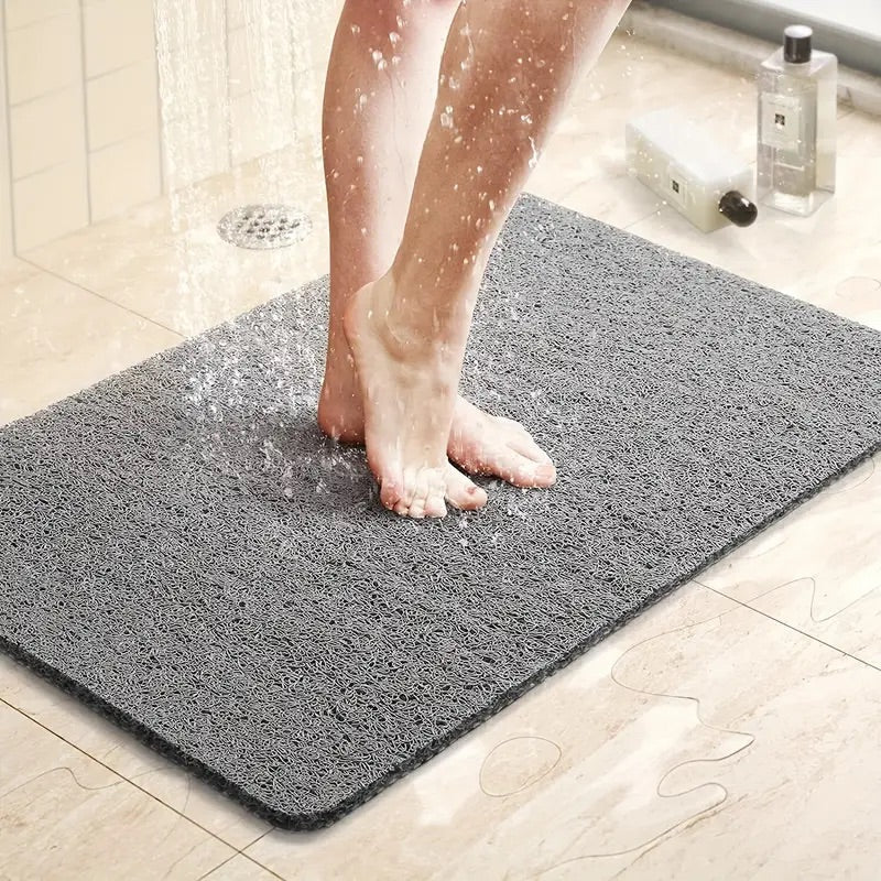  A bathroom anti-slip mat placed near a shower with a person stepping onto it, featuring a quick-dry design and textured surface for enhanced grip and safety.