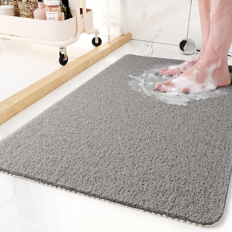  A bathroom anti-slip mat placed near a shower with a person stepping onto it, featuring a quick-dry design and textured surface for enhanced grip and safety.