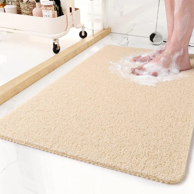  A bathroom anti-slip mat placed near a shower with a person stepping onto it, featuring a quick-dry design and textured surface for enhanced grip and safety.