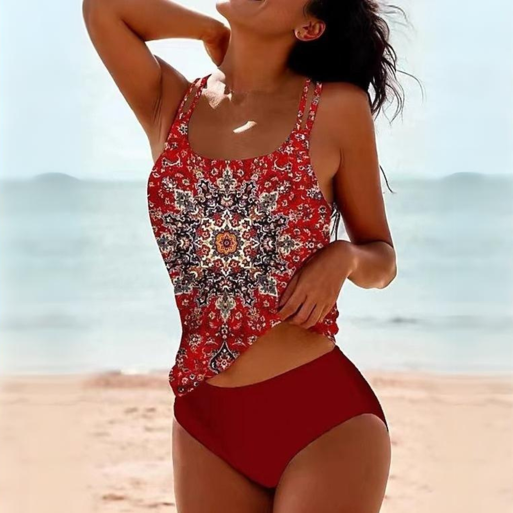 A woman wearing the Maya Women's Boho One-Piece Swimsuit with a vibrant mandala print and a stylish cut-out design at the waist, standing on a beach. This swimsuit features a boho-inspired look, perfect for adding unique flair to beach or poolside outfits.