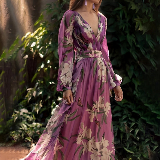 Woman wearing the Elara Women's Floral Chiffon Dress, an elegant long dress with a delicate floral design, flowy long sleeves, and a fitted waist, posing gracefully outdoors amidst lush greenery.