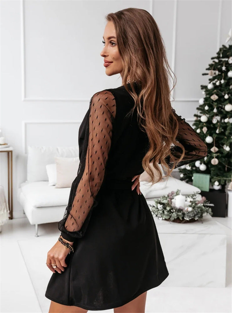 Woman wearing the Elena Women's Mesh Sleeve Wrap Dress, a mini dress with a flattering wrap design and stylish mesh sleeves, accessorized with layered necklaces and bracelets, posing elegantly in a chic indoor setting.