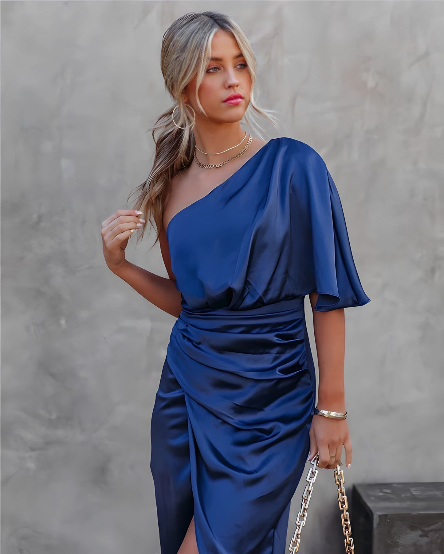 A woman standing in front of a decorated Christmas tree, wearing a stylish one-shoulder party dress with a ruched wrap design. The dress features an elegant silhouette, perfect for festive celebrations and special events. She is smiling and ready for the occasion.