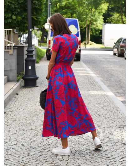 A woman walking down a street wearing the Lana Women's Elegant Wrap Dress, a casual midi dress with a flattering wrap design and tie waist, styled with sneakers and a woven handbag. This versatile dress is ideal for both casual outings and stylish gatherings.