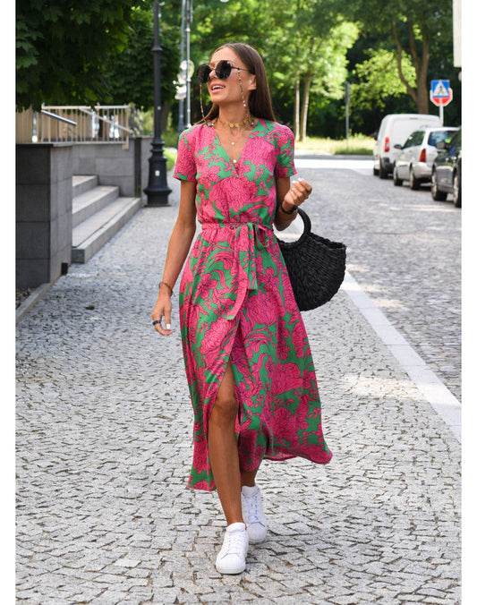 A woman walking down a street wearing the Lana Women's Elegant Wrap Dress, a casual midi dress with a flattering wrap design and tie waist, styled with sneakers and a woven handbag. This versatile dress is ideal for both casual outings and stylish gatherings.