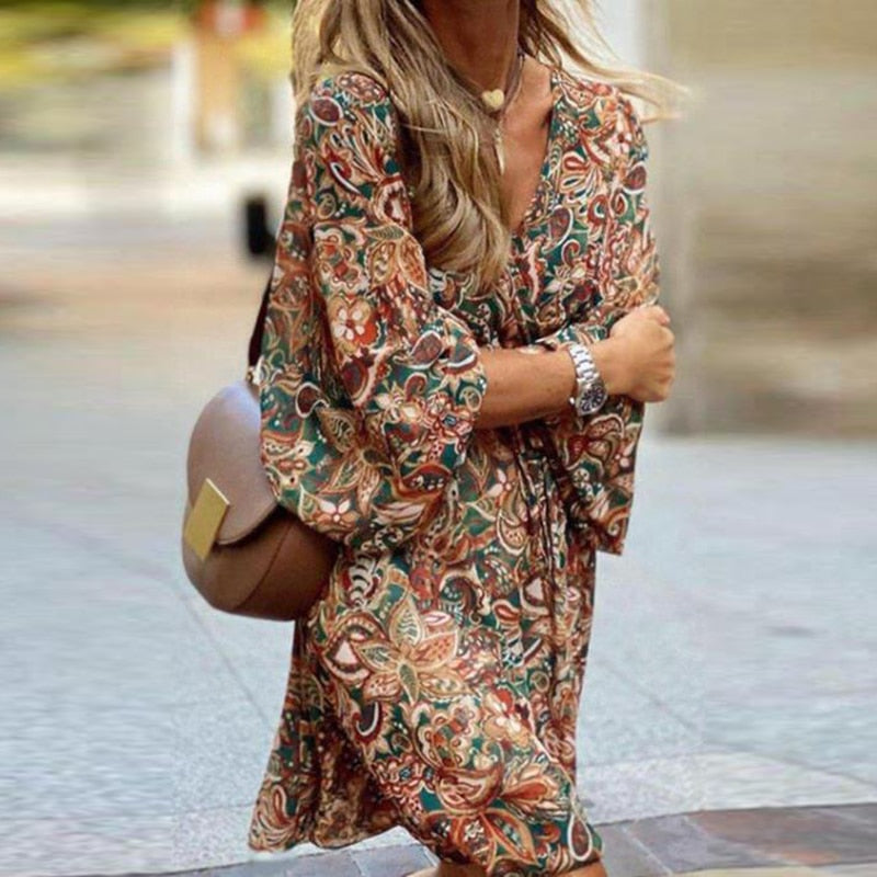 Model wearing the Esme Women's Boho Mini Dress with flowing sleeves and intricate paisley patterns, perfect for a chic, bohemian look. The dress offers a relaxed fit, ideal for casual outings or warm-weather events, styled with a crossbody bag and delicate accessories.