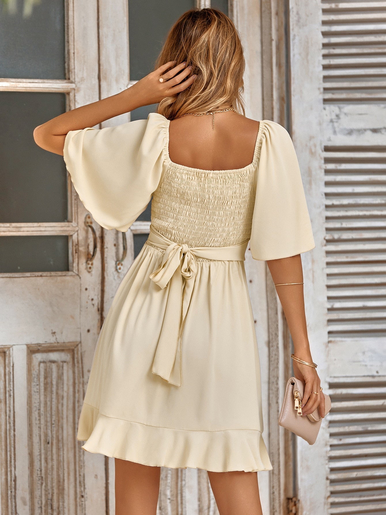 Elegant woman wearing a wrap dress with flutter sleeves and a ruffled hem, styled for a sophisticated and feminine look.