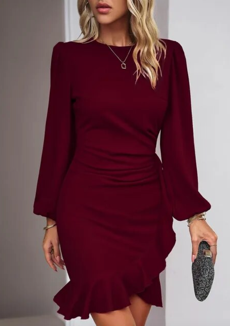 Woman wearing the Ava Women's Ruffled Hem Dress, a short dress with elegant long sleeves and a flattering ruffled hem, holding a small clutch and posing confidently indoors.