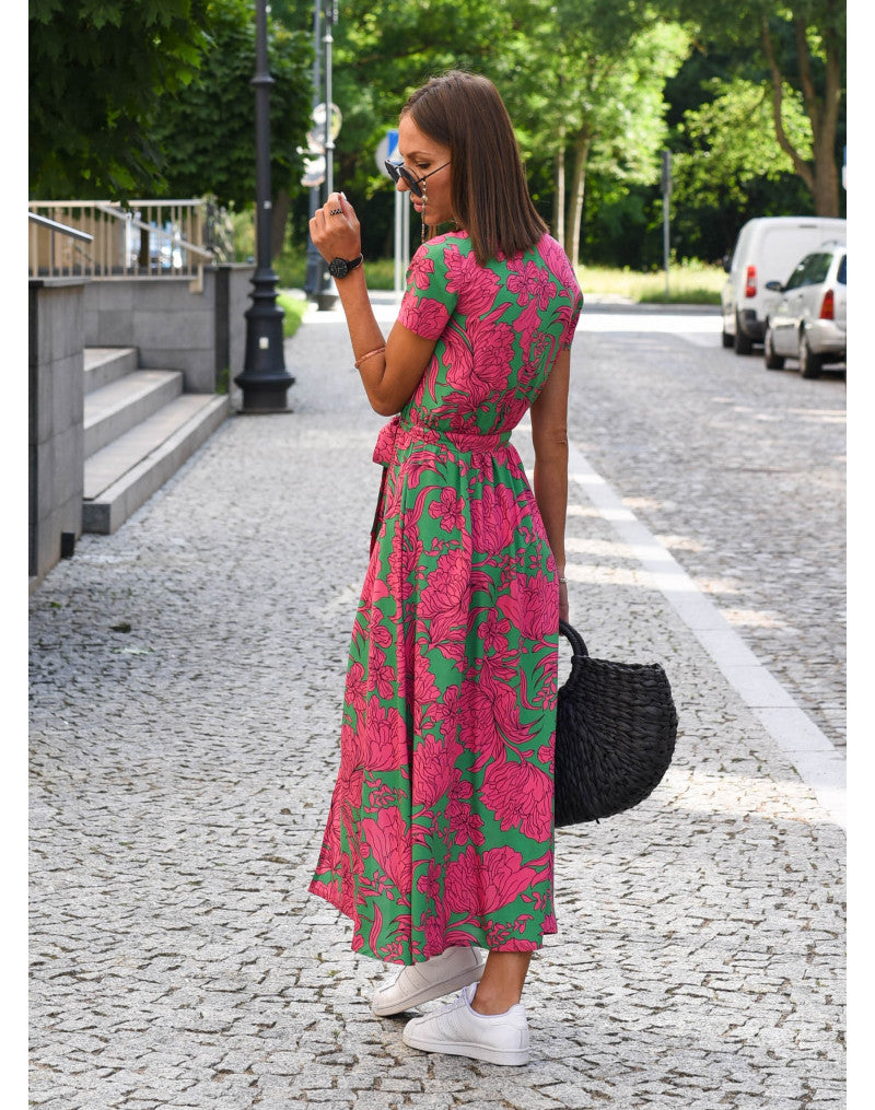 A woman walking down a street wearing the Lana Women's Elegant Wrap Dress, a casual midi dress with a flattering wrap design and tie waist, styled with sneakers and a woven handbag. This versatile dress is ideal for both casual outings and stylish gatherings.