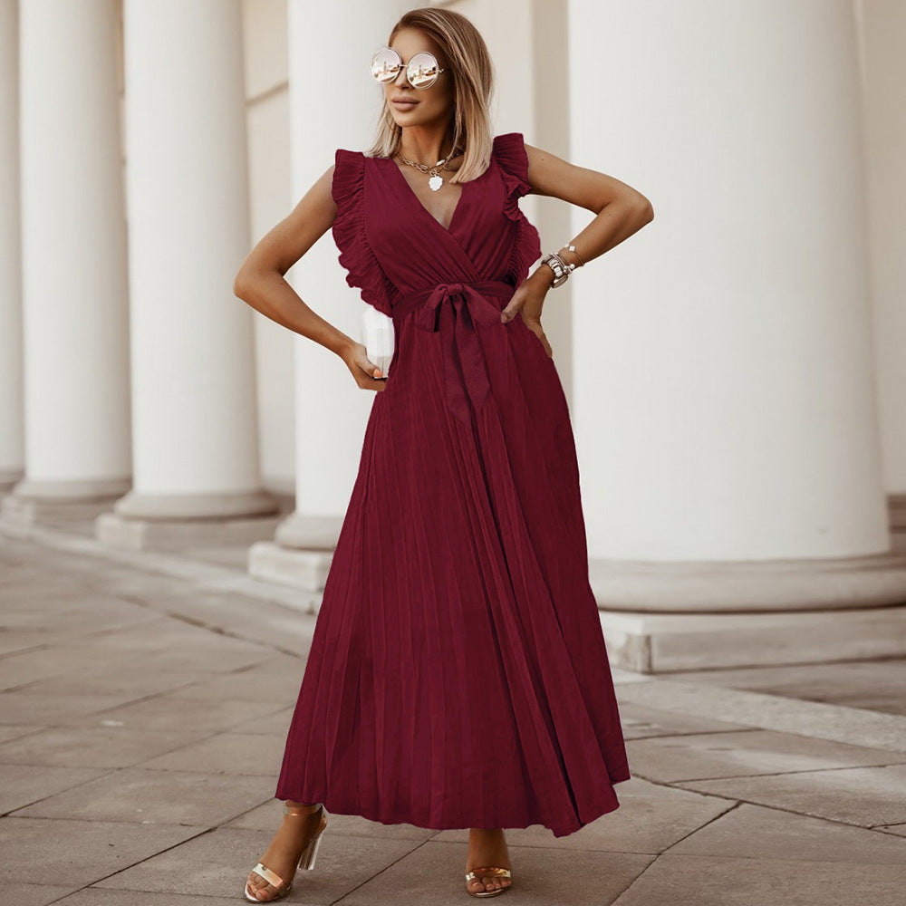 Woman wearing the Amara | Ruffled Sleeveless Pleated Maxi Dress, featuring elegant ruffles and a flowing pleated design, styled with heels and a handbag in an urban outdoor setting.