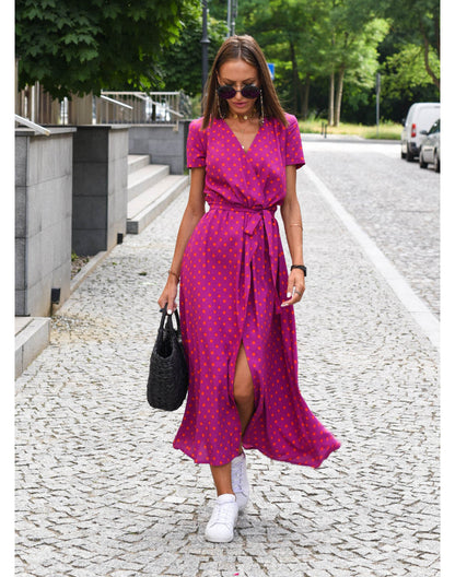 A woman walking down a street wearing the Lana Women's Elegant Wrap Dress, a casual midi dress with a flattering wrap design and tie waist, styled with sneakers and a woven handbag. This versatile dress is ideal for both casual outings and stylish gatherings.