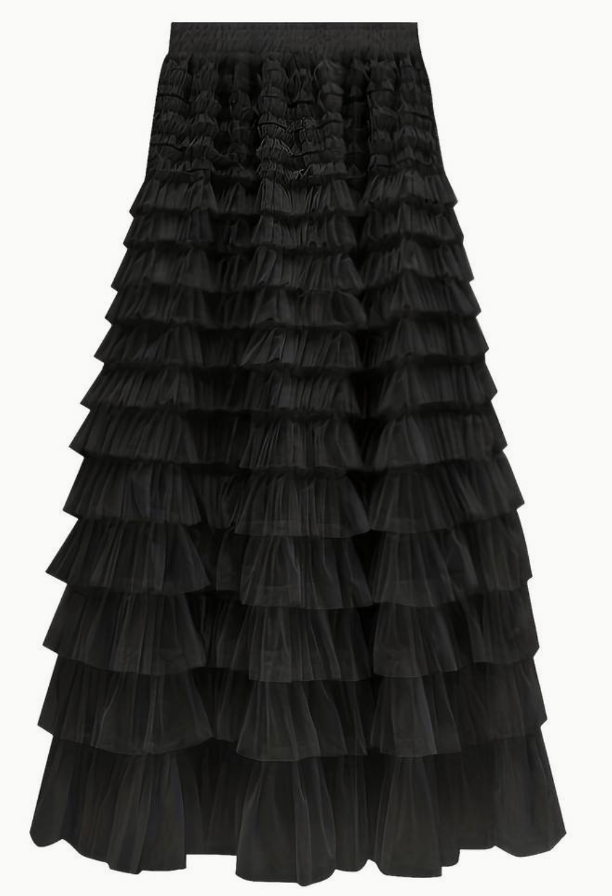 Woman wearing the Sophie Women's Layered Tulle Skirt, a ruffled skirt with multiple soft layers, creating a flowing and voluminous look, styled with a sleeveless top and accessories, standing on steps outdoors.