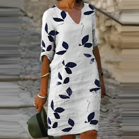 A woman wearing the Sophie Women's Leaf Print Shift Dress with an elegant V-neckline and a stylish leaf pattern. This dress features a relaxed, comfortable fit, ideal for casual or semi-formal occasions, offering a chic and nature-inspired look.