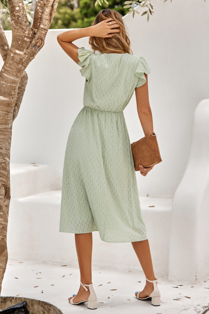 Model wearing the Grace Women's Midi Dress, featuring a flattering cinched waist, flutter sleeves, and a classic midi-length design, styled with sandals and a clutch for an elegant look.