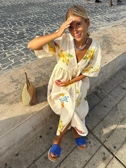 A fashionable woman taking a mirror selfie outdoors, wearing the Sophia | Women's Printed Midi Dress | Puff Sleeve Dress, styled with a woven bag, matching accessories, and flat sandals, showcasing the dress's elegant design and comfortable fit.