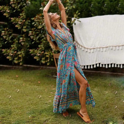 Full-length floral maxi dress with a flowing silhouette, flutter sleeves, and bohemian-inspired patterns, worn by a woman outdoors in a natural garden setting, capturing a sense of carefree elegance and movement.