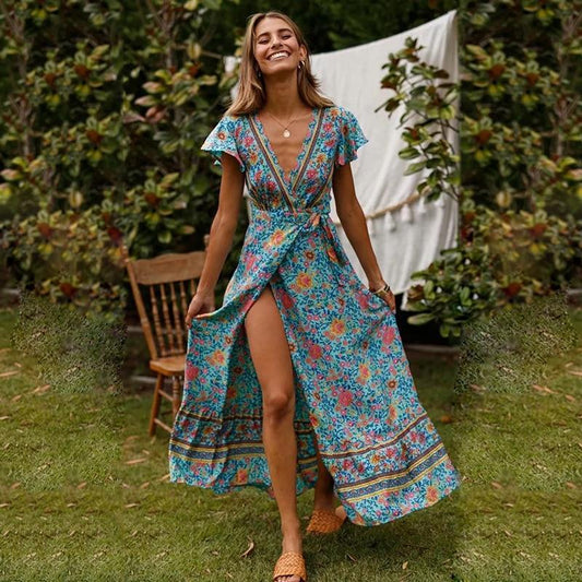 Full-length floral maxi dress with a flowing silhouette, flutter sleeves, and bohemian-inspired patterns, worn by a woman outdoors in a natural garden setting, capturing a sense of carefree elegance and movement.