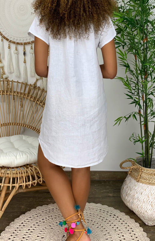 Woman wearing the Lily | Women's Casual Tunic Dress | Relaxed Fit Dress, accessorized with a long beaded necklace and casual shoes, standing next to a cactus and woven decor.