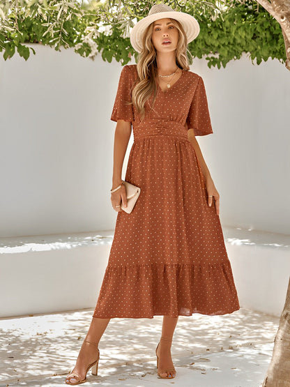 Woman wearing the Sophie | Elegant V-Neck Midi Dress with a flowing skirt and cinched waist, styled with a wide-brimmed hat and heels, perfect for an effortlessly chic and sophisticated look at any event.






