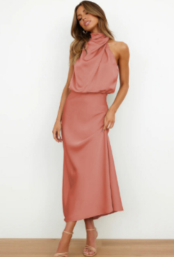 A woman wearing a sleeveless midi dress with an elegant draped neckline, standing outdoors in a stylish setting. The dress has a sleek and fitted silhouette, perfect for formal occasions or chic events. She is accessorized with minimalist heels for a polished, sophisticated look.