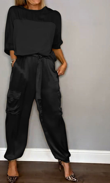 Image showcasing a stylish satin jumpsuit with a relaxed fit, featuring a belt at the waist and practical side pockets, perfect for an elegant yet comfortable look.