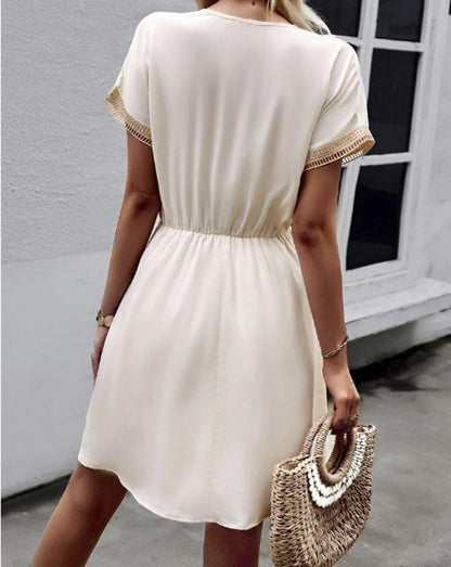 Woman wearing the Leah | Boho V-Neck Drawstring Dress with a relaxed fit and delicate detailing around the neckline. The dress is styled with a cinched waist, achieved through a drawstring, and paired with layered necklaces and a stylish handbag for a chic bohemian look.