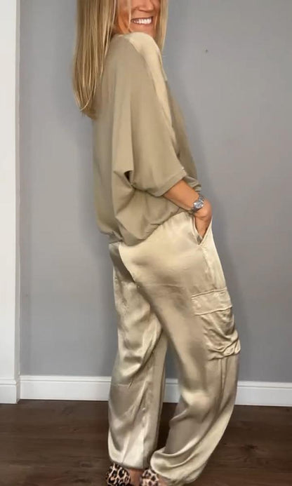 Image showcasing a stylish satin jumpsuit with a relaxed fit, featuring a belt at the waist and practical side pockets, perfect for an elegant yet comfortable look.