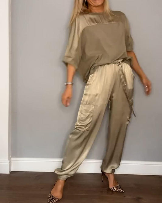 Image showcasing a stylish satin jumpsuit with a relaxed fit, featuring a belt at the waist and practical side pockets, perfect for an elegant yet comfortable look.