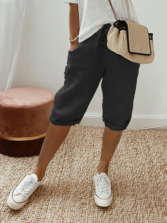 Women's relaxed-fit shorts paired with casual sneakers and a stylish woven bag, perfect for a comfortable and chic everyday look.