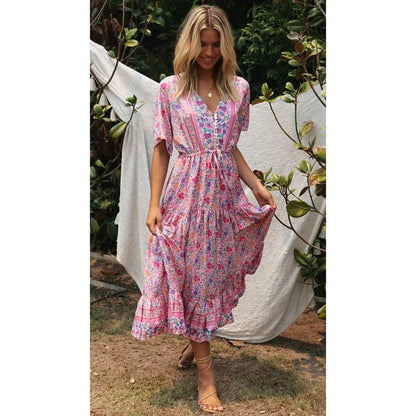 A woman sitting outdoors wearing a flowing midi dress with boho-inspired ruffles, featuring a flattering and relaxed design ideal for casual or special occasions.