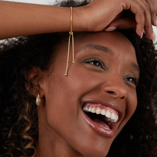 Smiling woman showcasing the Sophia Women's Adjustable Bracelet on her wrist, featuring a sleek and minimalist design. A stylish and versatile accessory perfect for any occasion.