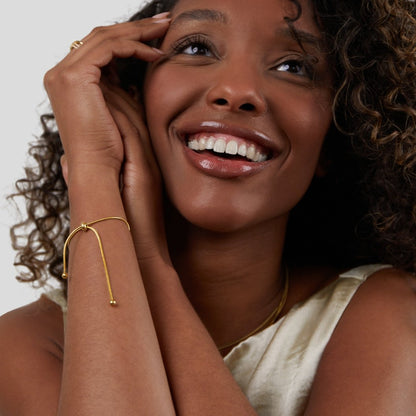 Smiling woman showcasing the Sophia Women's Adjustable Bracelet on her wrist, featuring a sleek and minimalist design. A stylish and versatile accessory perfect for any occasion.