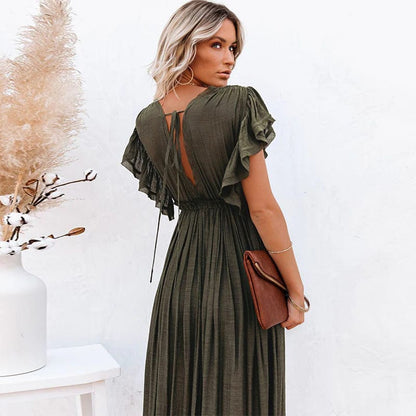 Woman wearing the Sienna Women's Button-Down Maxi Dress, a long, flowing dress with a relaxed fit and button-down front, posing elegantly with her hand in a pocket, holding a clutch, against a minimalist background.